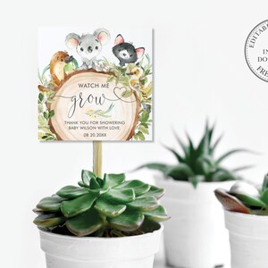 May include: A printable baby shower favour tag with a woodland theme. The tag features a koala, a black cat, and a platypus. The text on the tag reads "Watch me grow" and "Thank you for showering Baby Wilson with love. 08.20.20XX".