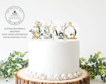 Puede incluir: Un adorno para pastel con la palabra "DOS" decorado con animales australianos y vegetación. Las letras son doradas con contornos blancos y los animales están en estilo acuarela.