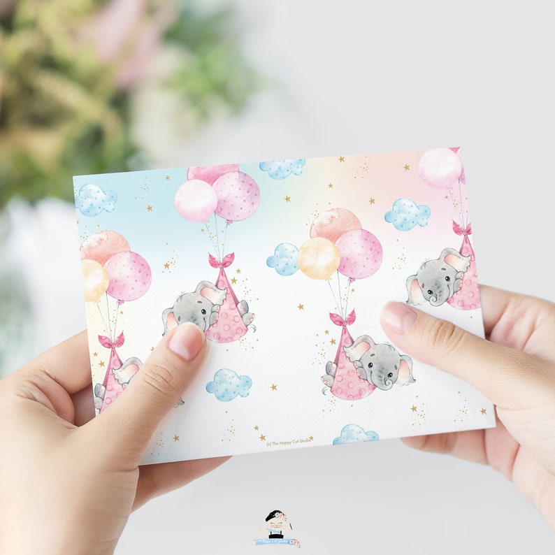 May include: A pink and blue patterned card with a repeating design of gray elephants holding onto pink and yellow balloons. The elephants are wearing pink party hats and there are gold stars and clouds in the background. The text "Lil' The Happy Cat Studio" is at the bottom of the card.