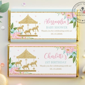 May include: Two printable chocolate bar wrappers featuring a gold glitter carousel design and floral accents. The top wrapper is light blue with the text "Alessandra's Baby Shower" and "Thank you for celebrating with us! 05.15.20XX". The bottom wrapper is pink with the text "Charlotte's 1st Birthday" and "Thank you for celebrating with us! 05.15.20XX".