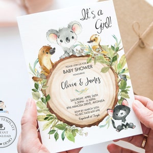 May include: A baby shower invitation with a watercolor illustration of a koala, a platypus, a kookaburra, and a Tasmanian devil. The invitation is on a woodgrain background with green leaves and the text "It's a Girl!" and "Please join us for a Baby Shower honoring Olivia & James".