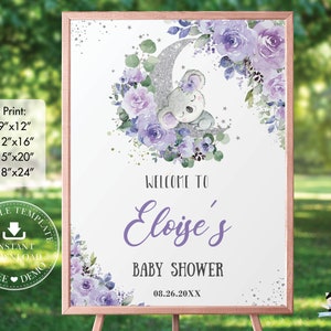 Op de afbeelding: Een babyborrelbord met een ros&eacute;gouden frame. Het bord heeft een aquarelontwerp met een slapende koala op een zilveren maan, omringd door paarse bloemen. De tekst luidt "Welkom bij Eloise's Baby Shower" en de datum.