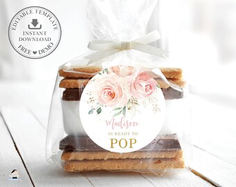 Könnte beinhalten: Ein runder, rosa-weißer Blumenaufkleber mit dem Text "Madison is ready to POP" auf einem durchsichtigen Plastikbeutel mit einem Stapel Graham-Cracker, Schokolade und Marshmallows.