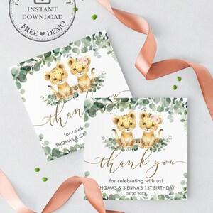 K&ouml;nnte beinhalten: Zwei Aquarell-Illustrationen von L&ouml;wenjungen mit rosa Blumen im Haar. Die Jungen sitzen auf einem Bett aus gr&uuml;nen Eukalyptusbl&auml;ttern. Der Text "Danke" ist in goldener Schrift geschrieben. Der Text "f&uuml;r das Feiern mit uns!" ist in Schwarz geschrieben. Der Text "THOMAS & SIENNA'S 1ST BIRTHDAY" ist in Schwarz geschrieben. Das Datum "08.20.20XX" ist in Schwarz geschrieben.