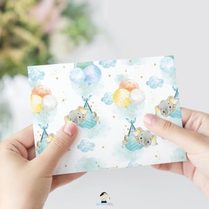 Pu&ograve; includere: Un biglietto bianco con un motivo ripetuto di elefanti grigi che tengono palloncini a strisce blu e bianche. I palloncini sono gialli, arancioni e blu. Lo sfondo &egrave; bianco con stelle dorate e nuvole blu.