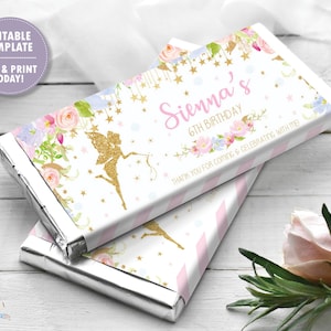 Puede incluir: Un envoltorio de barra de chocolate blanco con un diseño rosa y dorado que presenta un hada, flores y estrellas. El texto en el envoltorio dice "Sienna's 6th Birthday" y "Thank you for coming & celebrating with me!"