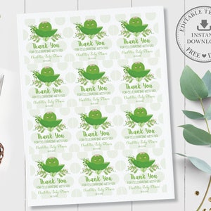 Op de afbeelding: Printbare bedankkaartjes met een cartoon-erwtendoos met een glimlachend gezicht. De kaartjes zijn groen en wit met de tekst "Bedankt voor het vieren met ons!" en "Charlotte's Baby Shower".