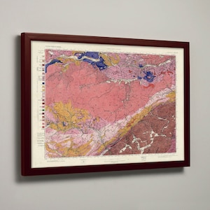 May include: A framed geological map of a region with a color-coded key. The map shows different rock formations and geological features in shades of pink, yellow, blue, and brown.