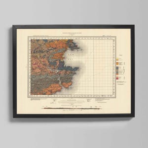 May include: Framed vintage map print with a black frame. The map features a detailed geological survey with various colors representing different land formations. The map includes a grid, text, and a legend. The print is displayed on a light gray wall.