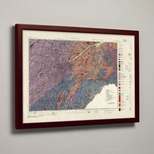 May include: A framed geological map with a burgundy-colored wooden frame. The map features a detailed, colorful illustration of the terrain, with various colors representing different geological formations. The map is mounted on a white background.
