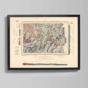 May include: Framed vintage geological map with a black frame. The map features a detailed illustration with various colors, including pink, green, and blue, depicting geological formations. The map is mounted on a cream-colored background.