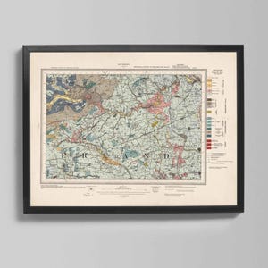 Op de afbeelding: Ingelijste vintage kaartprint met een gedetailleerd geologisch onderzoek van een regio. De kaart toont een complex netwerk van lijnen en kleurgecodeerde gebieden, met tekstlabels en een sleutel. De lijst is zwart en de kaart is gemonteerd op een crèmekleurige achtergrond.