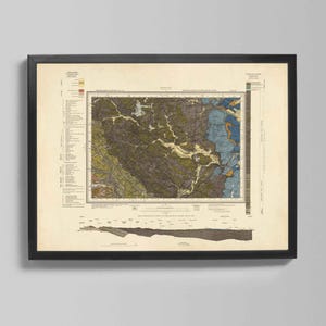 Puede incluir: Impresión enmarcada de un mapa geológico con marco negro. El mapa presenta una ilustración detallada con varios colores, incluyendo tonos de verde, marrón, azul y amarillo. La impresión incluye texto y una clave a la izquierda y una leyenda vertical a la derecha.