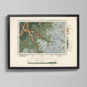Op de afbeelding: Ingelijste vintage kaartprint met een gedetailleerd geologisch onderzoek. De kaart toont verschillende kleuren, waaronder groen, blauw en bruin, die verschillende geografische kenmerken aangeven. De print zit in een zwart frame, geschikt voor thuis of op kantoor.