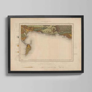 May include: Framed vintage map print featuring a detailed geographical illustration with a coastal region. The map displays various land features in shades of brown, green, and yellow, set against a beige background. The map is enclosed in a black frame.