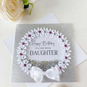 Peut inclure: Une carte de v&oelig;ux argent&eacute;e &agrave; paillettes avec une couronne de marguerites blanches et un n&oelig;ud blanc. La carte dit "Joyeux anniversaire &agrave; une fille tr&egrave;s sp&eacute;ciale".