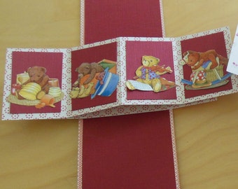 May include: A red and white paper card with a pop-up design featuring four teddy bears. Each bear is dressed in different clothing and holding different objects. The card is decorated with small red dots.