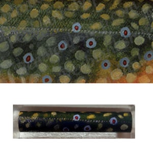 May include: Close-up of a section of a fish, showcasing a pattern of olive green, yellow, and brown scales. The scales feature small blue and red circular markings. Below, a cylindrical object with a similar pattern is displayed.