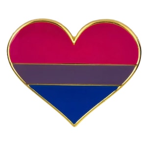 Pode incluir: Um broche em forma de coração com as cores da bandeira do orgulho bissexual: rosa, roxo e azul.