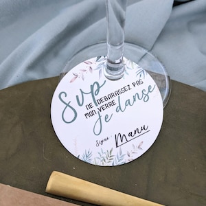 May include: A white round card with a green floral design and the text "Sup, ne debarrassez pas mon verre, je danse, signe Manu".