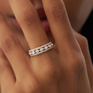 May include: A gold band ring with three rows of marquise-shaped diamonds.
