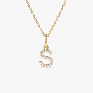 May include: A gold-coloured necklace featuring a pendant in the shape of the letter "S". The pendant is set with small, clear gemstones. The chain is delicate and gold-coloured, creating a simple and elegant piece of jewellery.