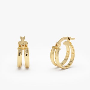 May include: A pair of gold hoop earrings with a double band design. The earrings have a hinged closure.