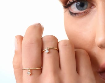 May include: Two gold rings with small diamond accents. The rings are worn on the finger of a person's hand.