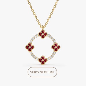 Puede incluir: Un collar de oro con un colgante que presenta un círculo de pequeños diamantes y cuatro acentos de flores de rubí rojo.