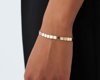 May include: A gold bracelet with a chain made of square links.