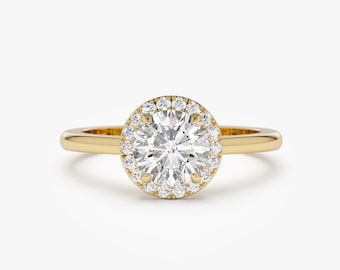 Op de afbeelding: Een gouden verlovingsring met een ronde centrale diamant omgeven door een halo van kleinere diamanten.