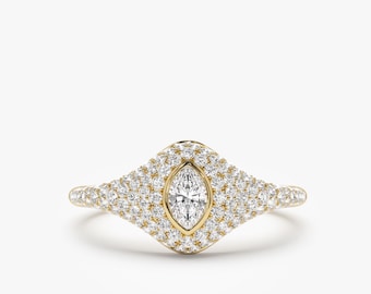 May include: A gold ring featuring a marquise-shaped diamond set within a halo of smaller diamonds. The ring has a delicate, curved band.
