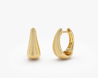 May include: A pair of gold hoop earrings with a textured, ribbed design. The earrings are a simple, elegant style.