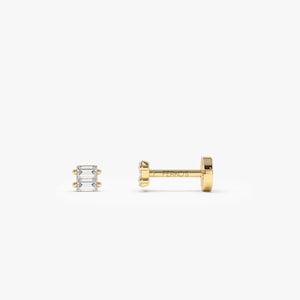 May include: A pair of gold earrings with rectangular, clear gemstones. One earring is shown from the side, displaying a post and backing. The other earring is shown from the front, with three gemstones.
