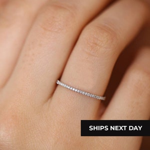 Puede incluir: Un fino anillo de banda de plata con una fila de pequeños diamantes.