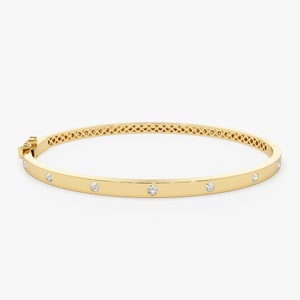 May include: A gold bangle bracelet with a row of small diamonds set into the band.