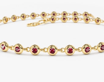 May include: A gold chain necklace with small red gemstones. The necklace has a delicate design and is perfect for everyday wear.