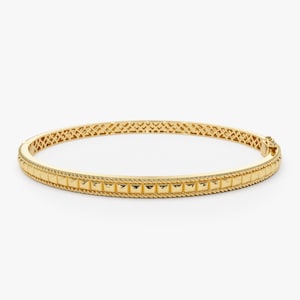 May include: A gold bangle bracelet with a textured design. The bracelet has a rope-like edge and a row of square-shaped accents.