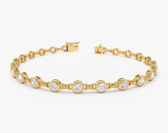 Puede incluir: Una pulsera dorada con una serie de diamantes redondos engastados en biseles. La pulsera tiene un diseño de cadena delicada y un cierre seguro. Los diamantes están espaciados uniformemente a lo largo de la cadena, creando un aspecto brillante y elegante.
