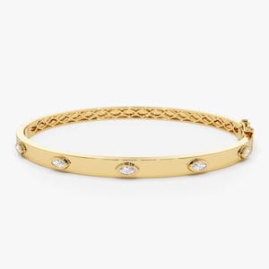 May include: A gold bangle bracelet with a polished finish and five marquise-shaped diamonds set into the band.