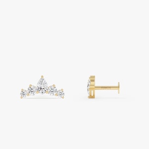 Könnte beinhalten: Ein goldener Ohrstecker mit einem zentralen birnenförmigen Diamanten, flankiert von vier runden Diamanten in kronenartiger Anordnung. Der Stift ist von der Seite sichtbar, wobei das Wort FERKO'S auf der flachen Rückseite eingraviert ist.