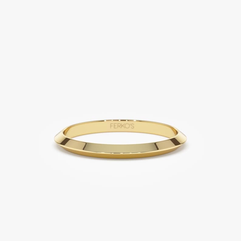 May include: A gold band ring with a slightly pointed edge. The ring is engraved with the text "FERKO'S".