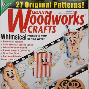 Peut inclure: Couverture du magazine "Creative Woodworks & Crafts" de février 2011, présentant des projets de menuiserie fantaisistes. On y voit des personnages de nourriture de dessins animés, avec le texte "27 Original Patterns!" et "Scrollsawing For Veterans Program."