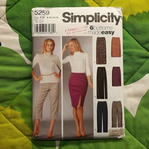May include: Simplicity sewing pattern 5259 featuring a woman in a white turtleneck and a burgundy skirt with a front slit. The pattern includes options for six different skirt styles. The pattern size is KK 8,10,12,14.