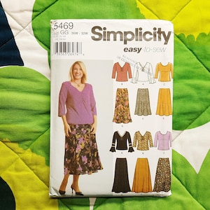 May include: A Simplicity sewing pattern package showing a woman in a purple top and floral skirt. The package includes illustrations of various tops and skirts. The size is GG, 26W-32W.