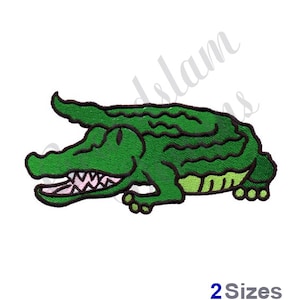May include: Green alligator with a toothy grin, lying on its belly with its legs tucked in. The alligator is a cartoon-style illustration with black outlines.