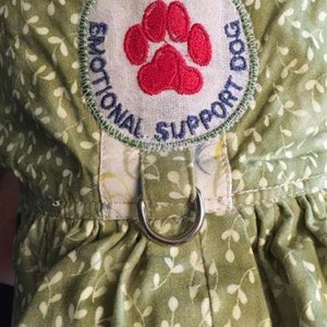 May include: Green fabric dog harness with a white patch that says "Emotional Support Dog" with a red paw print in the center.