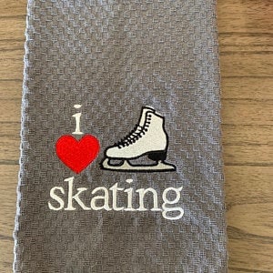 May include: Gray kitchen towel with white embroidery that says "I love skating" with a red heart and a white ice skate.