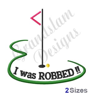 May include: Embroidered design of a golf green with a flag, a golf ball, and a golf club. The text "I was ROBBED!!" is written on the green.