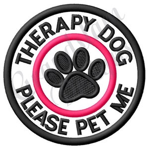 Op de afbeelding: Zwarte en witte geborduurde patch met een roze cirkel rond een pootafdruk. De tekst luidt "Therapy Dog Please Pet Me".